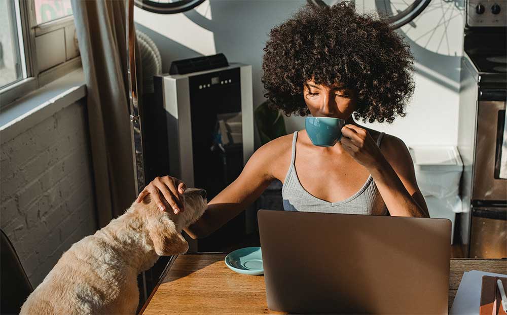 Woman drinking coffee and petting a dog